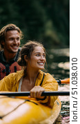 Adventurers enjoy kayaking on a serene lake surrounded by lush forests during a sunny afternoon. Стоковое AI-изображение, AI-художник Сергей Толмачёв / Фотобанк Лори