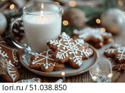Christmas gingerbread cookies decorated with icing and burning candle creating cozy atmosphere. Стоковое AI-изображение, AI-художник Иван Рябоконь / Фотобанк Лори