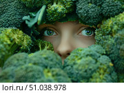 Woman with green eyes peeking through broccoli florets, promoting healthy diet and lifestyle. Стоковое AI-изображение, AI-художник Иван Рябоконь / Фотобанк Лори