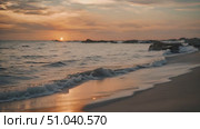 Sun slowly sets below the horizon, casting a warm glow over the water at the beach. Стоковое видео, видеограф Данила Большаков / Фотобанк Лори