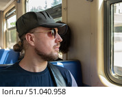 Пассажир пригородного электропоезда смотрит в окно. Стоковое фото, фотограф Лариса Веселова / Фотобанк Лори