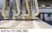 Close-up of multi-head CNC machine actively milling a workpiece, creating sawdust that is being collected by large corrugated pipes. Automated, high-precision process of modern woodworking. Стоковое фото, фотограф Елена Никишина / Фотобанк Лори