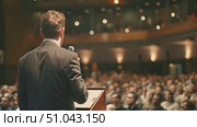 A man stands at a podium addressing an audience in a public setting. Стоковое AI-видео, аниматор Данила Большаков / Фотобанк Лори