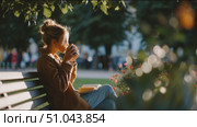 Young woman enjoys coffee while reading a book in a park during a sunny afternoon. Стоковое AI-видео, аниматор Сергей Толмачёв / Фотобанк Лори