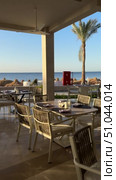 Luxury Arabian resort Empty tables and chairs along white buildings Round tables and chairs at an open-air restaurant An empty cafe, restaurant terrace in an urban environment midst lush vegetation greenery. Seating, vintage tables and chairs served for guests. Luxurious reception table Tableware on tablecloths.Interior of restaurant with orange chairs, tables, brick walls. Empty eatery features bar counter, loft design, modern lighting, large windows. Cafe is ready to serve food, beverages for clients. Стоковое видео, видеограф Zita Khasanova / Фотобанк Лори