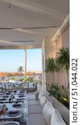 Luxury Arabian resort Empty tables and chairs along white buildings Round tables and chairs at an open-air restaurant An empty cafe, restaurant terrace in an urban environment amid-st lush vegetation greenery. Seating, vintage tables and chairs served for guests. Luxurious reception table Tableware on tablecloths.Interior of restaurant with orange chairs, tables, brick walls. Empty eatery features bar counter, loft design, modern lighting, large windows. Cafe is ready to serve food, beverages for clients. Стоковое видео, видеограф Zita Khasanova / Фотобанк Лори