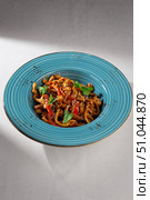 Traditional Korean chicken udon noodles with vegetables, mushrooms, cilantro and sesame seeds served in a rustic blue ceramic bowl on white background. Стоковое фото, фотограф Aleksandr Gavrilychev / Фотобанк Лори