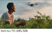 Man controls drone over lush fields during sunset in captivating outdoor setting. Стоковое AI-видео, аниматор Сергей Толмачёв / Фотобанк Лори