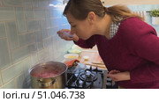 A woman stands by the stove, carefully stirring a pot of borscht filled with vibrant red beets, carrots, and cabbage, as a delicious aroma fills the kitchen. Стоковое видео, видеограф Ирина Старикова / Фотобанк Лори