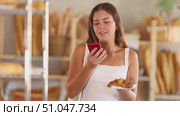 Woman checks calories of croissant using app on phone Young woman checks calorie content of croissant using app on her phone. Стоковое видео, видеограф Яков Филимонов / Фотобанк Лори