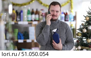While shopping, man talks on phone, walks along windows and consults with wife about purchases. Buyer in household chemicals store speaks on phone, answers call on Christmas Eve. Стоковое видео, видеограф Яков Филимонов / Фотобанк Лори