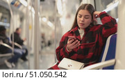 Young woman is sitting in subway wagon, chatting in social network while late on undeground, getting to work. She is in transport, travels in urban transport. Стоковое видео, видеограф Яков Филимонов / Фотобанк Лори