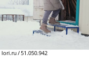 Female legs in winter boots and a long down jacket climbs an iron ladder into a garage during a snowfall, side view. Стоковое видео, видеограф Кашапова Эльвира / Фотобанк Лори