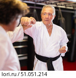 Older karate fighter practicing paired kumite in dojo. Стоковое фото, фотограф Яков Филимонов / Фотобанк Лори