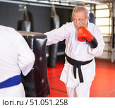 Older karate practitioner punching shield in training dojo. Стоковое фото, фотограф Яков Филимонов / Фотобанк Лори