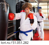 Man punching heavy bag in martial arts class. Стоковое фото, фотограф Яков Филимонов / Фотобанк Лори