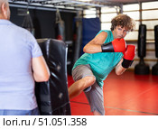 Man practicing foot strikes on kick shield with trainer. Стоковое фото, фотограф Яков Филимонов / Фотобанк Лори