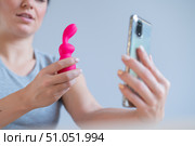 A woman demonstrates a modern clitoral vibrator in the form of a rabbit in her video blog on her smartphone. Girl advise sex toy. Стоковое фото, фотограф Михаил Решетников / Фотобанк Лори