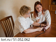 Mother and daughter dressed in light clothes versed in the smartphone. A woman shows how to use a smartphone for her elderly mother. Стоковое фото, фотограф Михаил Решетников / Фотобанк Лори