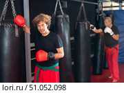 Martial artist in boxing gloves resting against punchbag in dojo. Стоковое фото, фотограф Яков Филимонов / Фотобанк Лори
