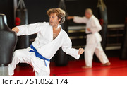 Man in white kimono trains in gym - he punches sports dummy. Стоковое фото, фотограф Яков Филимонов / Фотобанк Лори