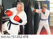 Elderly man in white kimono practices punching punching bag. Стоковое фото, фотограф Яков Филимонов / Фотобанк Лори