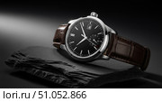 Closeup of luxury men's watch on black slate background, elegant timepiece with black dial, chronograph, and brown leather crocodile strap. Стоковое AI-изображение, AI-художник Павел Муравьев / Фотобанк Лори