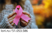 Hands Holding a Pink Ribbon Symbolizing Breast Cancer Awareness During a Sunny Day in a Natural Setting. Стоковое AI-изображение, AI-художник Юлия Гапеенко / Фотобанк Лори