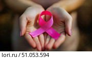 Hands Holding a Pink Ribbon Symbolizing Breast Cancer Awareness During a Sunny Day in a Natural Setting. Стоковое AI-изображение, AI-художник Юлия Гапеенко / Фотобанк Лори
