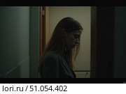 A woman stands in a softly lit hallway, her gaze lowered as she seems lost in thought. Shadows envelop the space, creating an atmosphere of contemplation and intrigue in the quiet evening. Стоковое AI-изображение, AI-художник Ольга Игнашина / Фотобанк Лори