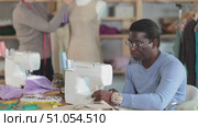 Tailor sewing at machine while colleague working with mannequin. Стоковое видео, видеограф Яков Филимонов / Фотобанк Лори