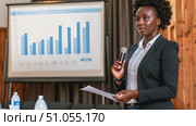 Confident African American woman is standing in front of a microphone, holding a piece of paper while preparing to speak. Стоковое AI-видео, аниматор Данила Большаков / Фотобанк Лори
