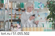 Elderly woman buyer scanning qr code for shampoo in pharmacy. Стоковое видео, видеограф Яков Филимонов / Фотобанк Лори