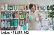 Among shop windows, man buyer leisurely examines goods and chooses glass cleaner spray. Стоковое видео, видеограф Яков Филимонов / Фотобанк Лори