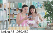Near display case in pharmacy, woman with daughter scans barcode on female pads, reads user manual. Client studies product in detail, collects information online. Стоковое видео, видеограф Яков Филимонов / Фотобанк Лори