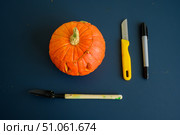 Little pumpkin with spiteful grimass, paper knife, pen, trowel over black background. Halloween concept, flat lay, top view. The process of making jack-o-lantern. flat lay. Стоковое фото, фотограф Михаил Решетников / Фотобанк Лори