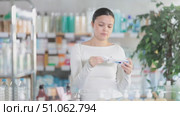 Asian woman holds an ointment for psoriasis and eczema in her hands, she carefully reads the instructions before buying. Стоковое видео, видеограф Яков Филимонов / Фотобанк Лори