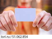 Person holding blank white card in both hands in outdoor urban setting. Стоковое фото, фотограф Raquel Corcoles Mendez / Фотобанк Лори