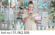 Attentive pregnant woman scanning barcode on feminine pads in chemist's shop. Стоковое видео, видеограф Яков Филимонов / Фотобанк Лори
