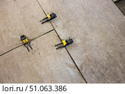 Tile leveling clips are installed between laid floor tiles, ensuring a uniform distance between them and a level surface. Стоковое фото, фотограф Коханова Наталья / Фотобанк Лори