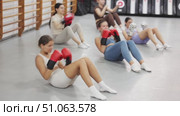 Young women do abdominal exercises and practice punches in boxing gloves. Exercise to pump the abdominal muscles. Group boxing training. Стоковое видео, видеограф Яков Филимонов / Фотобанк Лори