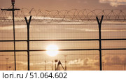 Sunset illuminating airport fence with barbed wire at dusk. Стоковое видео, видеограф Mikhail Davidovich / Фотобанк Лори