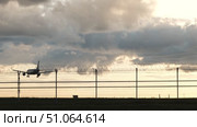 Passenger plane landing at airport behind barbed wire fence at sunset. Стоковое видео, видеограф Mikhail Davidovich / Фотобанк Лори