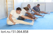 Men athletes are preparing for lesson in oriental martial arts and perform preliminary warm-up and legs stretching exercises. Стоковое видео, видеограф Яков Филимонов / Фотобанк Лори