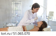 Professional young female aesthetician administering hardware procedure on woman in cosmetology clinic, using high frequency ultrasound head to open skin pores for deep penetration of nutrients. Стоковое видео, видеограф Яков Филимонов / Фотобанк Лори