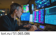 Professional working in a high-tech control room with multiple computer screens displaying data and graphs. Стоковое AI-видео, аниматор Сергей Толмачёв / Фотобанк Лори