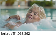 A content elderly woman unwinds with a leisurely swim outdoors as dusk falls. Стоковое AI-видео, аниматор Данила Большаков / Фотобанк Лори