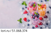Three glasses filled with colorful fruit pieces and ice cubes neatly arranged on a wooden table. Стоковое AI-видео, аниматор Данила Большаков / Фотобанк Лори