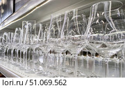 Row of various clear stemware, including wine and champagne glasses, is lined up on store shelf. Great for concepts of glassware, barware and celebratory events. Стоковое фото, фотограф Елена Никишина / Фотобанк Лори