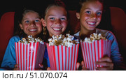 Three youthful females stand in a movie theater, each holding a bucket of popcorn as they prepare to enjoy a film together. Стоковое AI-видео, аниматор Данила Большаков / Фотобанк Лори